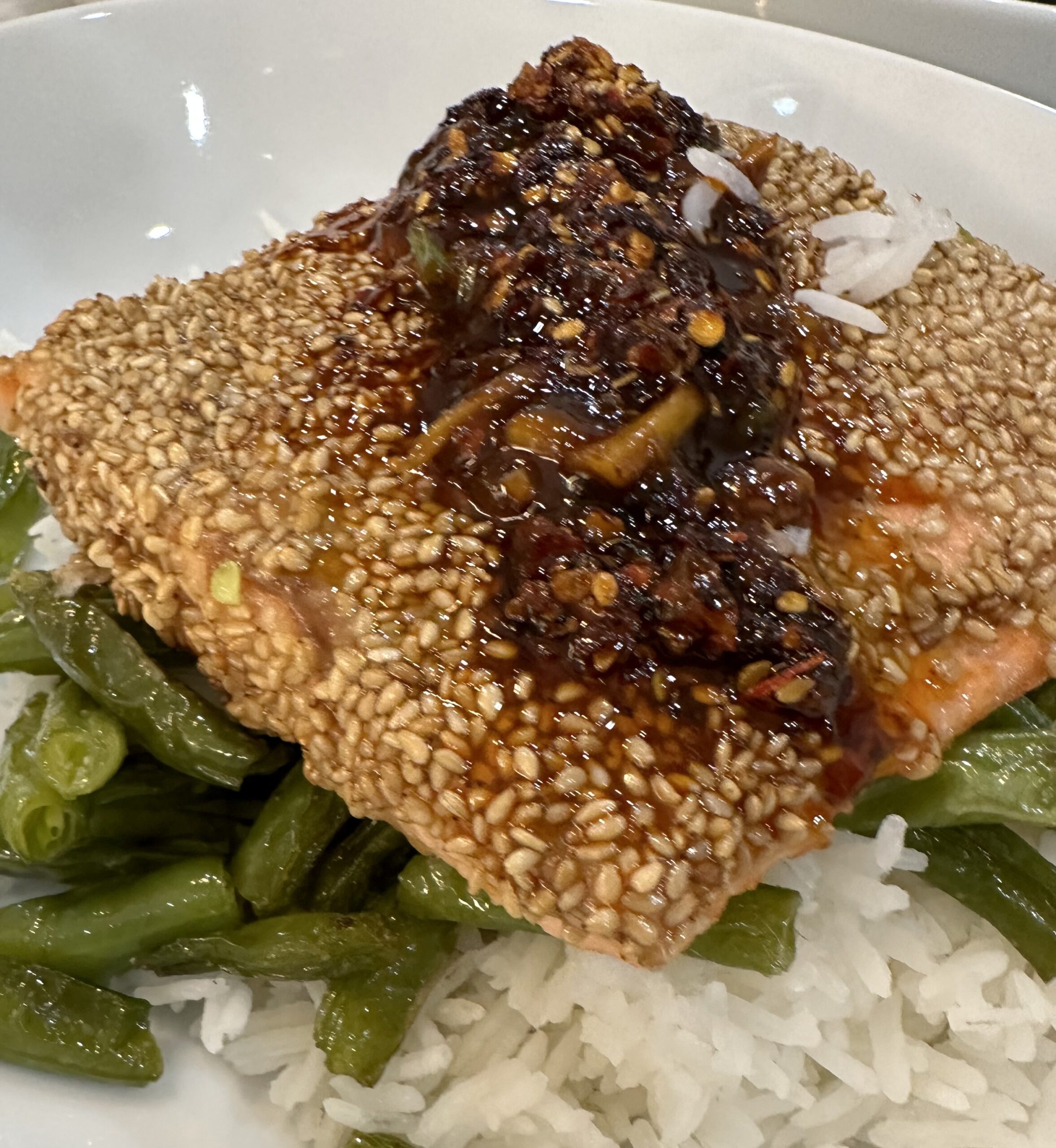 Sesame crusted salmon with ginger and garlic topping on green beans and rice
